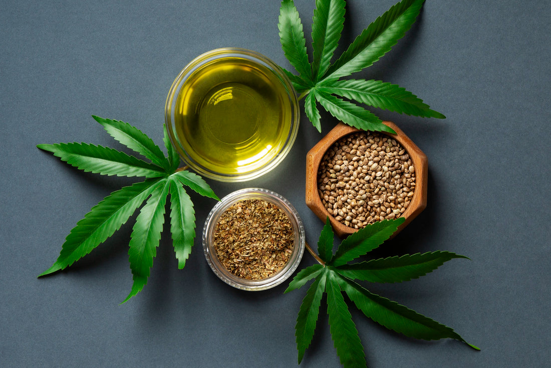 Image: Three bowls containing CBD oils and other extracts surrounded by 3 cannabis leaves on a blue background