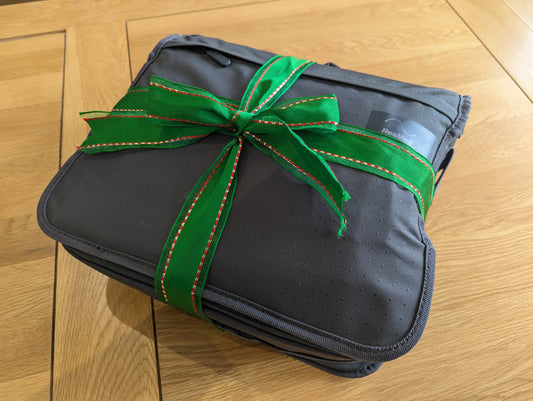 Image: A grey CPAP equipment bag wrapped in a green ribbon and tied-off in a bow.
